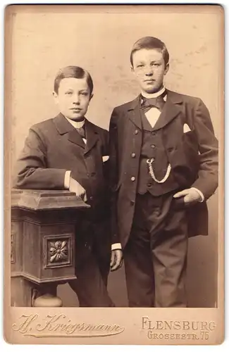 Fotografie H. Kriegsmann, Flensburg, Grossestrasse 75, Portrait zwei halbwüchsige Knaben im Anzug mit Fliege