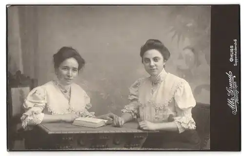 Fotografie Albr. Grund, Ohligs, Suppenheiderstrasse 6, Portrait zwei bürgerliche Damen mit Buch am Tisch sitzend