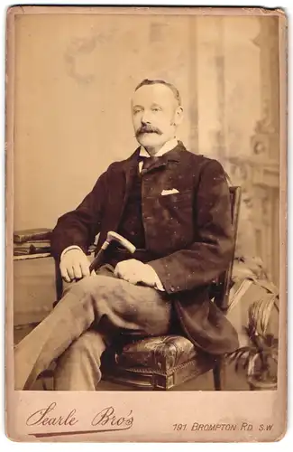 Fotografie Searle Bro`s, London-SW, 191, Brompton Road, Portrait bürgerlicher Herr mit Stock auf Stuhl sitzend