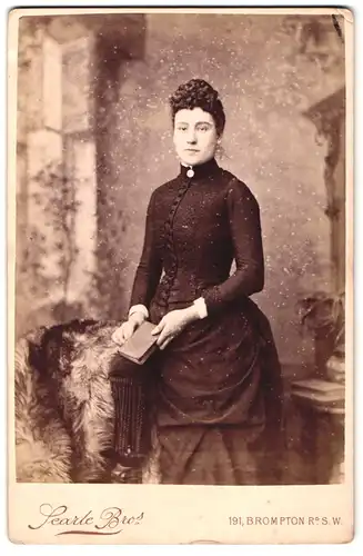 Fotografie Searle Bro`s, London-SW, 191, Brompton Road, Portrait bürgerliche Dame mit Buch an Stuhl gelehnt