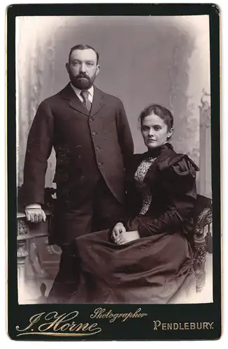 Fotografie J. Horne, Pendlebury, Portrait bürgerliches Paar in zeitgenössischer Kleidung