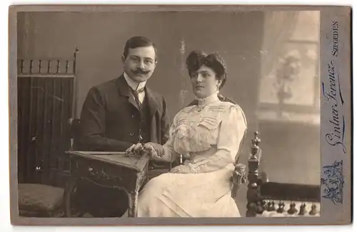 Fotografie Ginter Ferencz, Szegeden, Széchényi Tér 2, Ehepaar in Sonntagskleidung am Beistelltisch