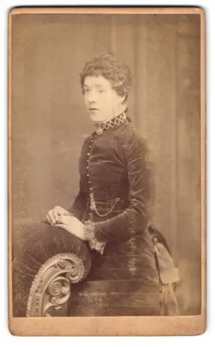 Fotografie Henry Death, London, 119, Camberwell Road, Portrait junge Dame im Samtkleid an Sessel gelehnt