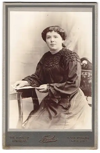 Fotografie Fred, Leeds, 15 New Briggate, Portrait bürgerliche Dame mit Buch am Tisch sitzend