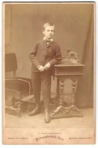 Fotografie Robert W. Thrupp, Birmingham, 66, New Street, Portrait halbwüchsiger Knabe im Anzug an Schreibtisch gelehnt