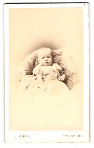 Fotografie James Owen, Salisbury, 29, Catherine Street, Portrait niedliches Kleinkind im Kleid auf Fell sitzend