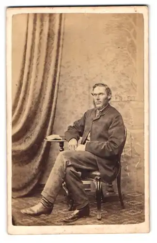 Fotografie M. Cuthbert, York, Corner of New Street and Davygate, Portrait modisch gekleideter Herr am Tisch sitzend