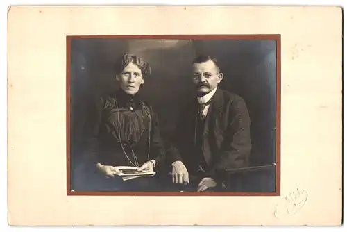Fotografie Ph. Uhl, Giessen, Portrait älters Paar in hübscher Kleidung mit Zeitung