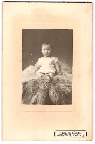 Fotografie Atelier Rüsing, Vohwinkel, Kirchstrasse 3, Portrait niedliches Kleinkind im weissen Hemd auf Fell sitzend