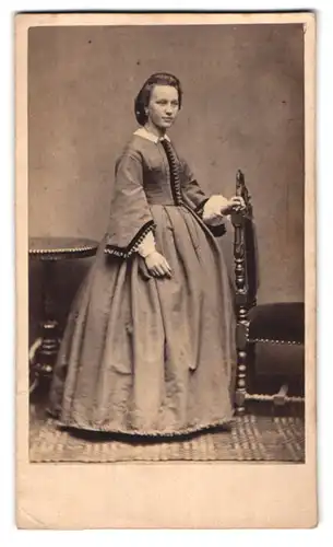 Fotografie unbekannter Fotograf und Ort, Junge Frau mit zurückgekämmten Haar in Kleid mit Reifrock