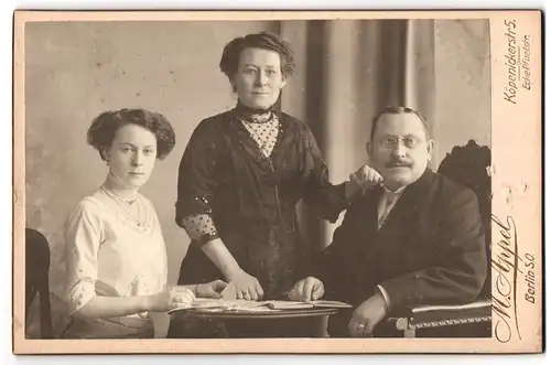 Fotografie M. Appel, Berlin-NO, Neue Königs-Strasse 1, Portrait bürgerliches Paar mit einer Tochter am Tisch
