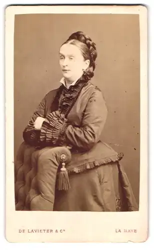 Fotografie De Lavieter & Co., La Haye, Dame mit aufwändig geschmücktem Kleid trägt die Haare zum Kranz geflochten
