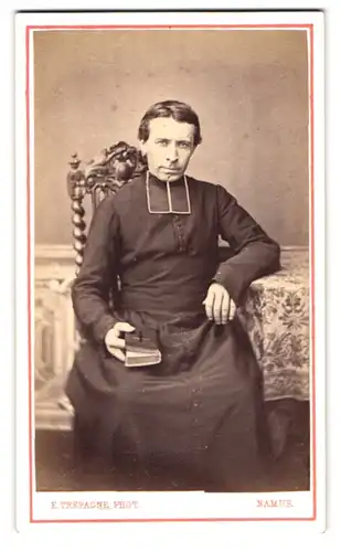 Fotografie E. Trepagne, Namur, 10, rue du President, Portrait junger charmanter Geistlicher im Talar mit Gebetsbuch