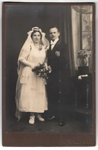 Fotografie Otto Richter, Radeberg, Pulsnitzerstrasse, Portrait junges Paar in Hochzeitskleidung mit Schleier und Blumen