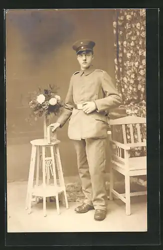 AK Uniformfoto, Soldat zum Bild an einem kleinen Tisch aufgestellt