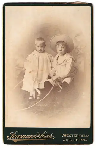 Fotografie Seaman & Sons, Chesterfield, Portrait kleiner Junge und Schwesterchen in hübscher Kleidung mit Reifen