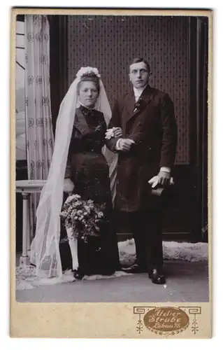 Fotografie Alex. Strube, Löbau i/S., Portrait modisch gekleidetes Hochzeitspaar mit Brautstrauss