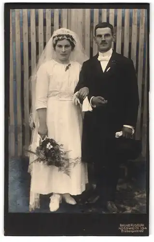 Fotografie Bruno Rudolph, Rosswein i /Sa., Brückenplatz 410, Portrait junges Paar in Hochzeitskleidung mit Blumen