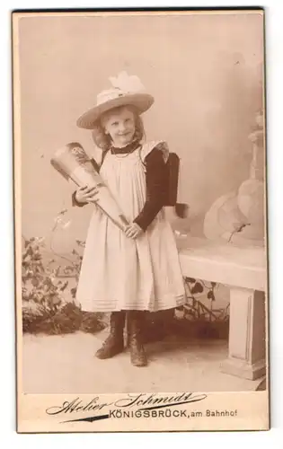 Fotografie Carl Schmidt, Königsbrück, Am Bahnhof, Portrait lächelndes Schulmädchen mit Zuckertüte und Schulranzen