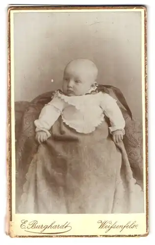 Fotografie E. Burghardt, Weissenfels, Baby mit fragendem Blick in weissem Spitzenkleid