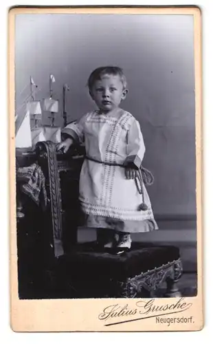 Fotografie Julius Grusche, Neugersdorf, Süsses Kind im Kleid neben Modellschiff