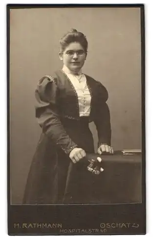 Fotografie H. Rathmann, Oschatz, Hospitalstrasse 40, Frau mit Hochsteckfrisur, Brille und Blumensträusschen