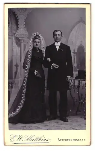 Fotografie E. W. Matthias, Seifhennersdorf, Ehepaar im schwarzen Kleid mit Schleier und Zylinder