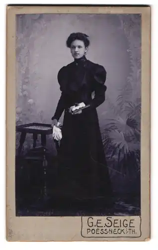 Fotografie G. E. Seige, Poessneck in Thüringen, Portrait junge Dame im schwarzen Kleid mit Buch