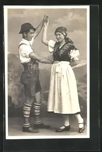 Foto-AK Paar in Tracht beim Volkstanz in einer Studiokulisse