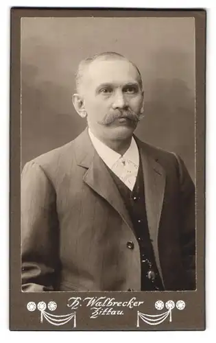 Fotografie H. Walbrecker, Zittau, Theodor Körner Allee, Portrait Mann mit Halbglatze und Walrossbart im Anzug