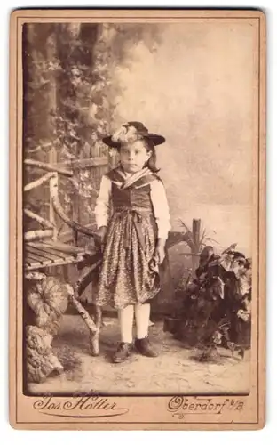 Fotografie Jos. Hotter, Oberdorf b. B., Portrait kleines Mädchen in Tracht steht vor einer Studiokulisse