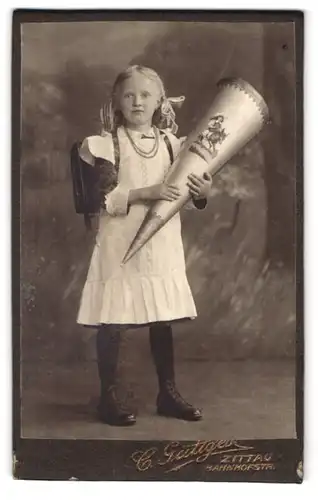 Fotografie C. Güttges, Zittau, Bahnhofstr. Portrait Mädchen im weissen Kleid mit Zuckertüte und Schulranzen