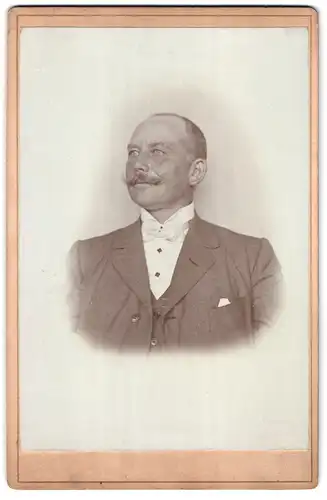 Fotografie Fotograf und Ort unbekannt, Portrait älterer Mann im Anzug mit Fliege und Moustache, Halbglatze