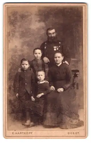 Fotografie E. Hartkopf, Soest, Soldat in Uniform mit Ordenspange nebst Familie im Foto-Atelier