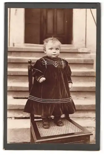 Fotografie Atelier Claus, Weissig-Weisser Hirsch, Portrait kleines blondes Kind im Samtkleidchen auf Stuhl stehend