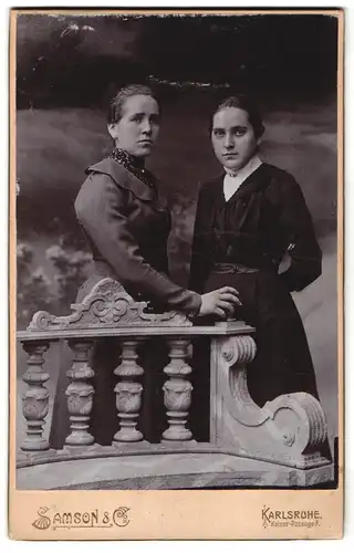 Fotografie Samson & Co, Karlsruhe, Kaiser-Passage 7, Zwei Damen mit zurückgebundenen Haaren stehen hinter Steinbank