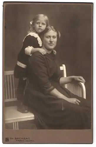 Fotografie Th. Backens, Marne i. Holst., Mutter sitzt auf Bank, Tochter steht hinter ihr