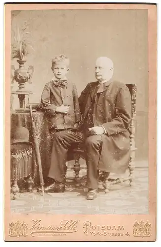 Fotografie Hermann Selle, Potsdam, York-Str. 4, Sitzender Herr in langem Mantel mit seinem Enkel