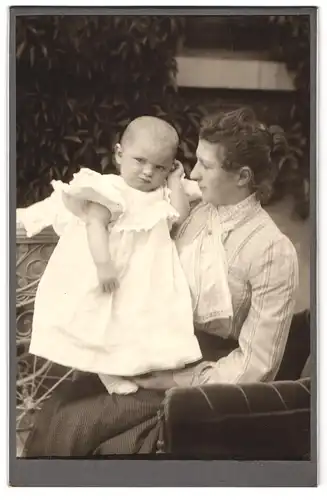 Fotografie Heinr. Meyer, Trier, Simeonstr. 14, Frau in gestreifter Bluse mit gepunktetem Rock hält ein Baby