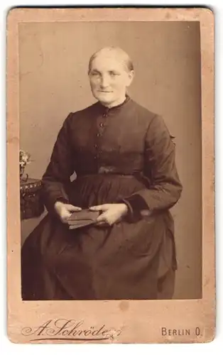 Fotografie A. Schörder, Berlin, Gr. Frankfurterstr. 117, Alte Dame in schlichtem Kleid mit Buch