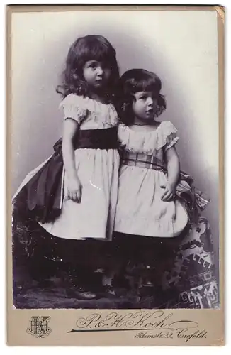 Fotografie P. & H. Koch, Crefeld, Rheinstrasse 32, Portrait zwei kleine Mädchen in hübschen Kleidern