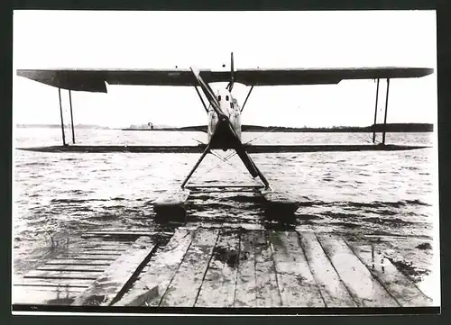 Fotografie Flugzeug, Doppeldecker-Wasserflugzeug vor einem Anleger