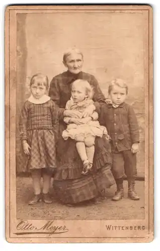 Fotografie Otto Meyer, Wittenberg, Markt 16, Portrait ältere Dame mit drei Kindern in zeitgenössischer Kleidung