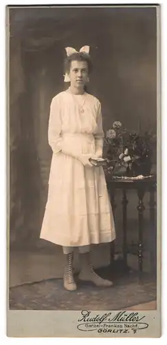 Fotografie Rudolf Müller, Görlitz, Portrait hübsches Mädchen mit Buch und Schnürstiefel im weissen Kleid