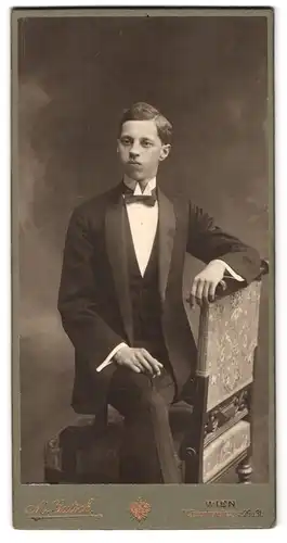 Fotografie M. Gutsch, Wien, Favoritenstr. 29 & 31, Portrait junger Mann elegant im Anzug auf einer Stuhllehne sitzend