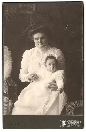 Fotografie A. Kreutzfeldt, Sonderburg, Portrait Mutter mit Kind im Taufkleidchen