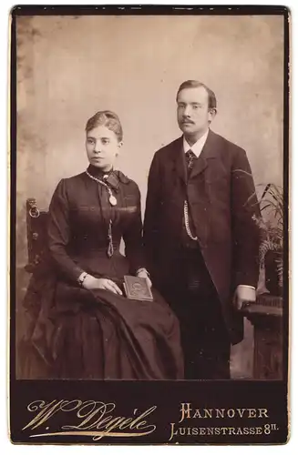 Fotografie W. Degèle, Hannover, Luisenstrasse 8, Herr im Anzug und Dame im tailliertem Kleid