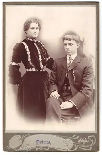 Fotografie John Holmes & Co, Manchester, 24 Market Place, Dame im Samtkleid und Herr im Anzug mit Krawatte
