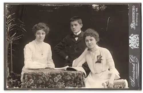 Fotografie Samson & Co, Magdeburg, Breiteweg 168, Zwei junge Damen mit gelocktem Haar mit jungem Burschen im Anzug