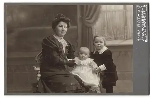 Fotografie W. Roth, Berlin- Schöneberg, Hauptstr. 20, Dame und ihr Sohn halten ein Kleinkind in weissem Kleidchen